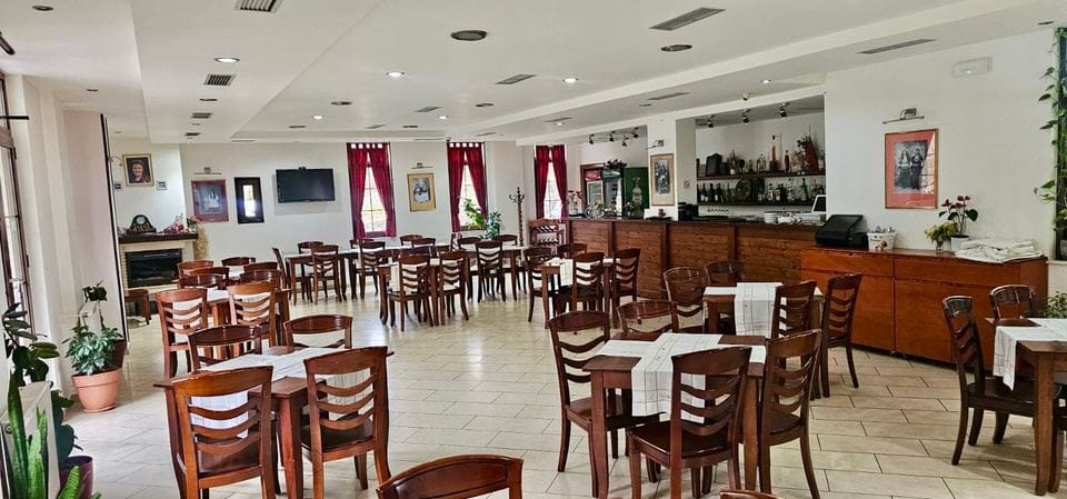 Restaurant dining room with wooden chairs, white table runners, a fireplace and a bar